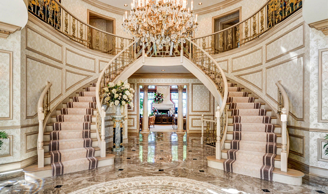 This magnificent double-staircase foyer is just the beginning of the plush amenities found inside this Lake Geneva, Wis., waterfront estate, listed by The Rauland Agency. Opposite page: The exterior of this fine home, which sits on more than 200 feet of prime lakefront.
